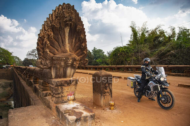 Hombre montando su moto de aventura sobre el Puente del Dragón en Camboya - foto de stock