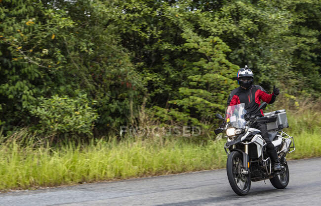 Человек едет на своем мотоцикле по ветреной дороге в Камбодже — стоковое фото