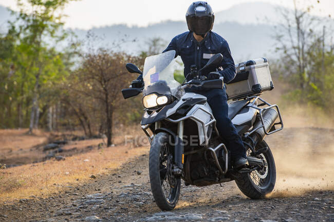 Hombre montando su moto de aventura en el camino de tierra en Camboya - foto de stock