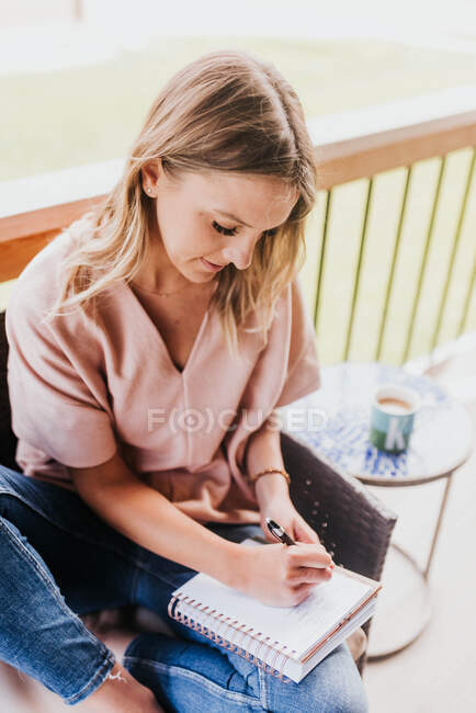 Belle jeune femme prenant des notes à la maison — Photo de stock
