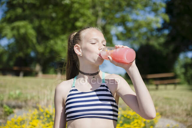 Між дівчиною в купальнику п'є рожевий лимонад на відкритому повітрі . — стокове фото