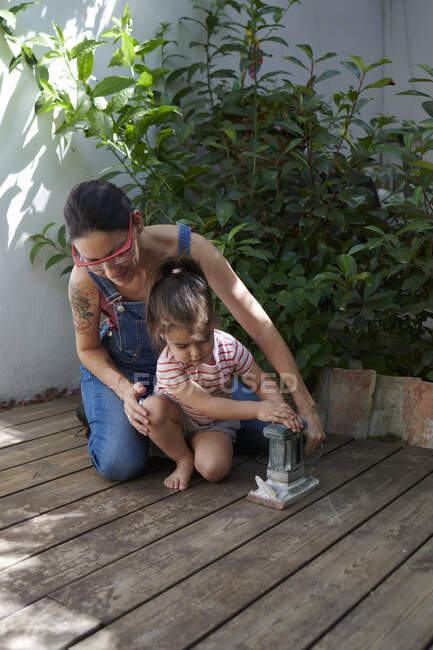 Mother and daughter sanding the wood in the garden — Stock Photo