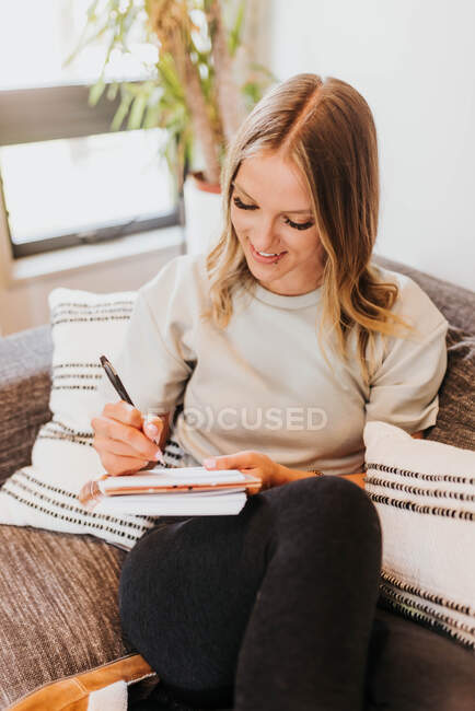 Hermosa mujer joven haciendo notas en casa - foto de stock