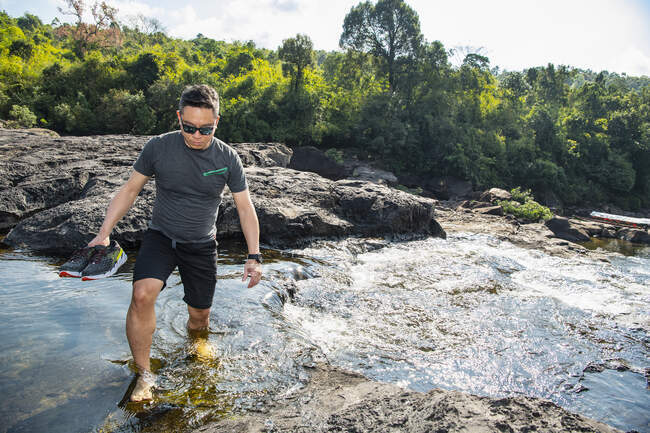 Mann watet durch Tatai-Fluss nahe Tatai-Wasserfall in Kambodscha — Stockfoto