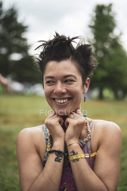 Non-binary asian smiles in colourful croptop at festival camp — Stock Photo