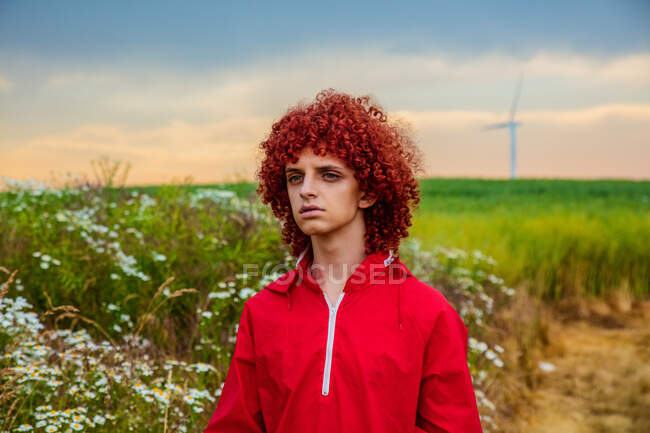 Молодой парень с рыжими кудрявыми волосами в спортивном костюме 80-х годов на поле — стоковое фото