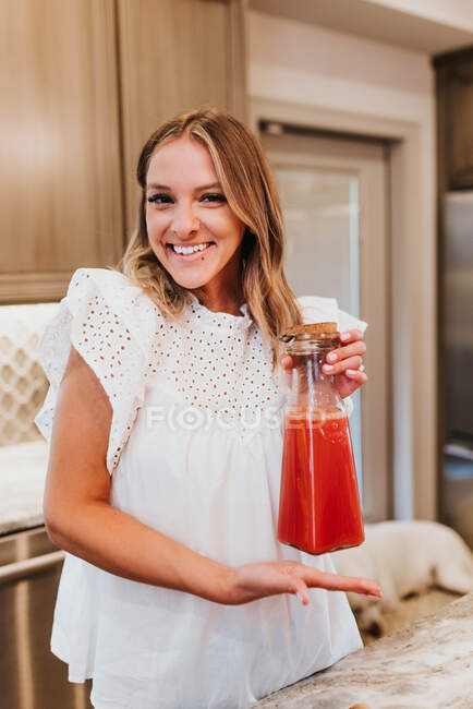 Bela jovem com suco em casa — Fotografia de Stock
