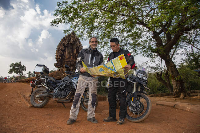 Двое мужчин смотрят на карту во время приключенческого мотопробега в Камбодии — стоковое фото