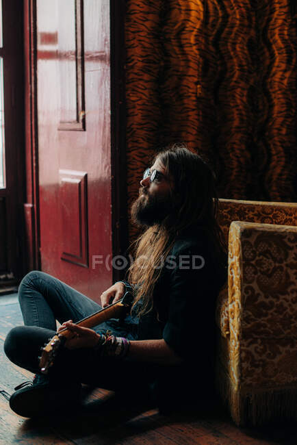 Музыкант сидит на полу и играет на гитаре — стоковое фото