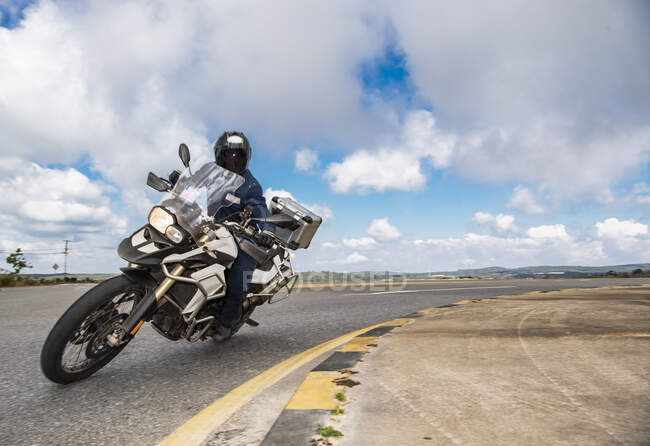 Hombre inclinado su moto de aventura a su vez en viaje por carretera en Camboya - foto de stock