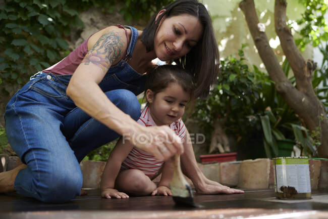 Une femme peignant le bois sur le sol — Photo de stock