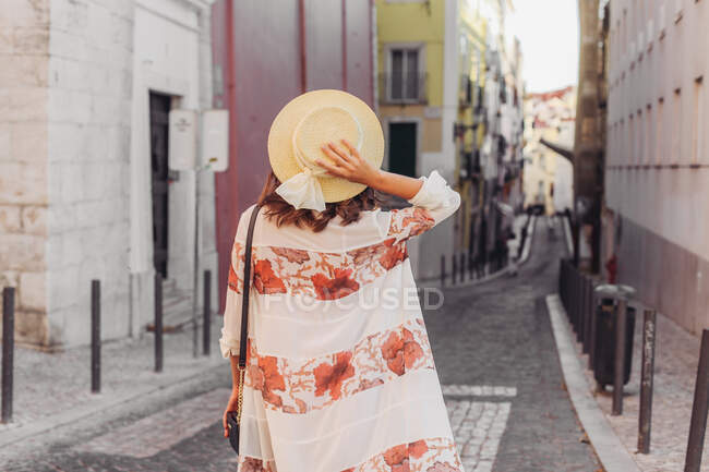 Jeune femme en chapeau marchant dans la rue — Photo de stock