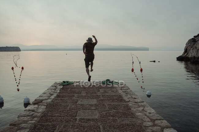 Mann springt von Steg ins Wasser. — Stockfoto
