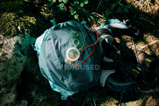 Brújula con mochila sobre fondo verde - foto de stock