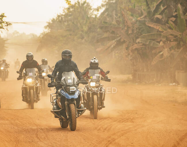 Groupe d'hommes conduisant leur moto d'aventure sur un chemin de terre au Cambodge — Photo de stock