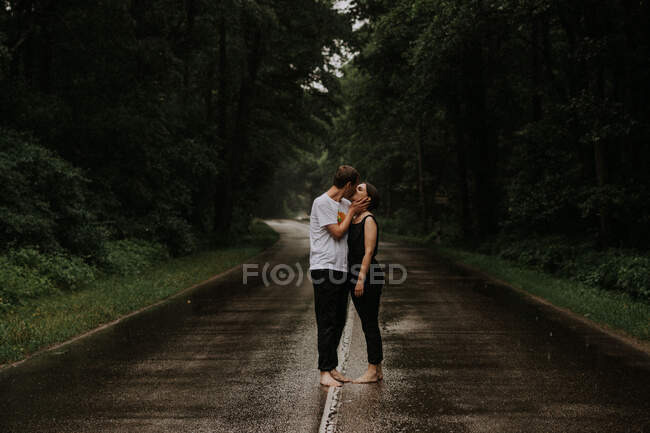 Una pareja enamorada besándose bajo la lluvia. - foto de stock
