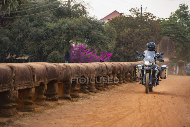 Людина їде на своєму пригодницькому мотоциклі над мостом дракона в Камбоджі. — стокове фото