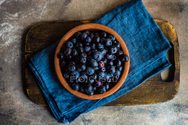 Bowl full of raw organic blueberries on wooden board — Stock Photo