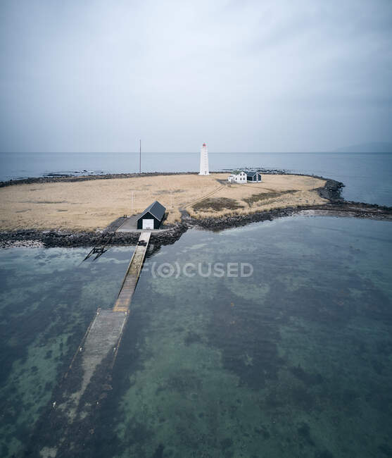 Luftaufnahme der sandigen Insel mit Häusern und weißem Leuchtturm inmitten des sauberen blauen Meeres in Island — Stockfoto