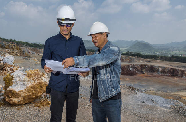 Engineers discussing survey plan at gravel mine in Thailand — Stock Photo