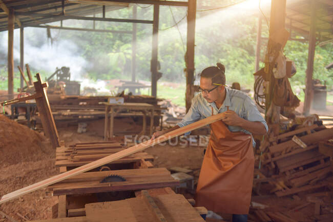 Geschickter Tischler, der in seiner Holzwerkstatt ein Stück Holz schneidet, Tischler, die in der Werkstatt Kreissäge im Vintage-Stil verwenden — Stockfoto