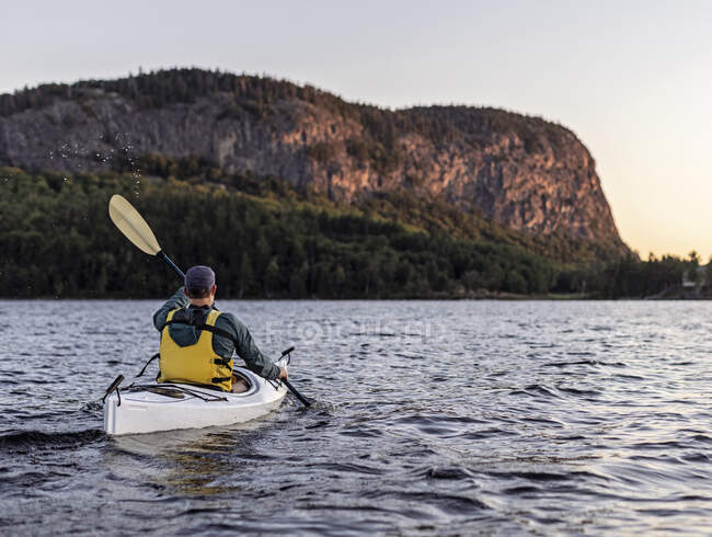 Hombre rema en Kayak a través de Moosehead Lake hacia Mount Kineo, Maine - foto de stock
