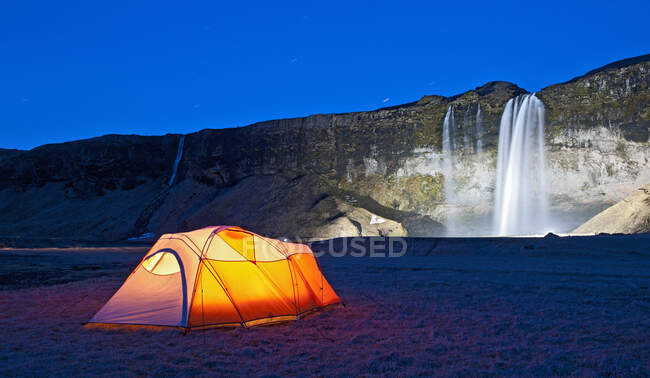 Illuminato tenda presso la cascata Seljalandsfoss nel sud dell'Islanda — Foto stock