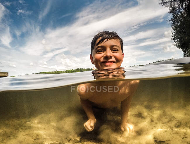 Split water view of happy boy in a lake on a warm summer day. — Stock Photo
