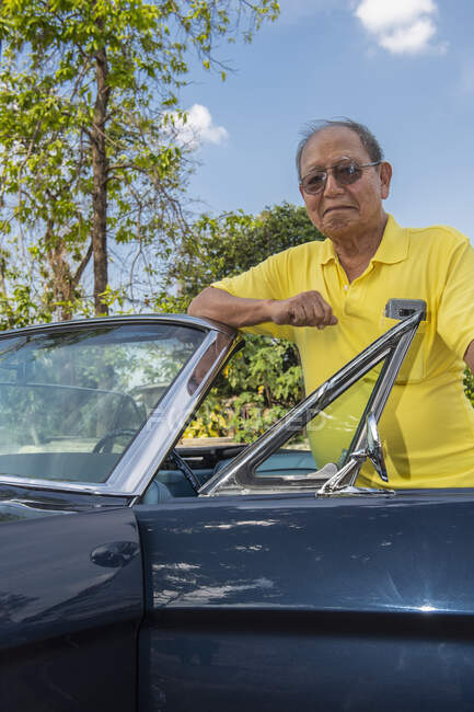Adulto sênior posando orgulhoso com seu carro conversível restaurado — Fotografia de Stock