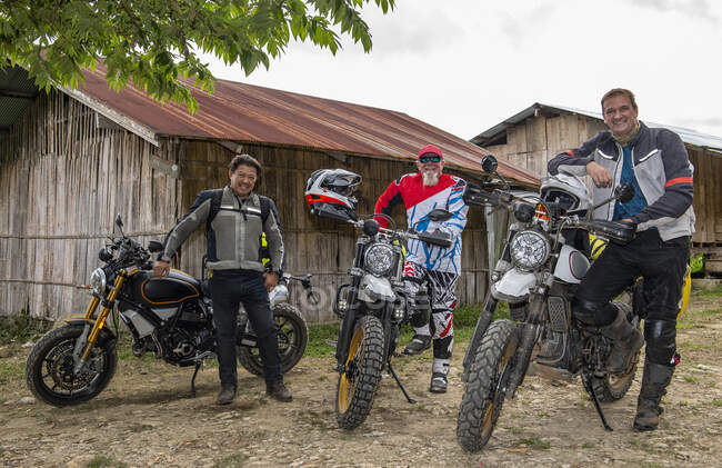 Чоловіки зупиняються з мотоциклом у тайському селі. — стокове фото