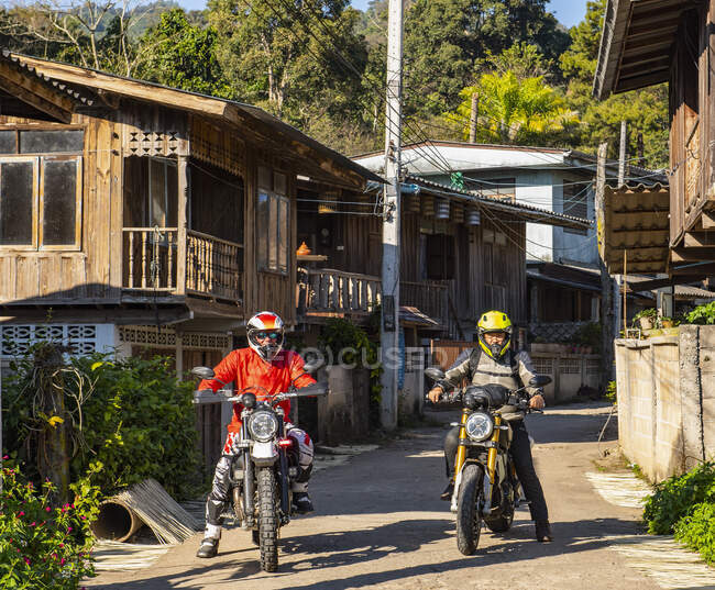 Hombres parando en la carretera con su motocicleta en la aldea tailandesa - foto de stock