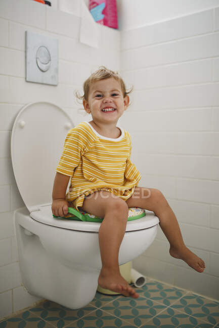 Ritratto di ragazza felice seduta sul water a casa — Foto stock