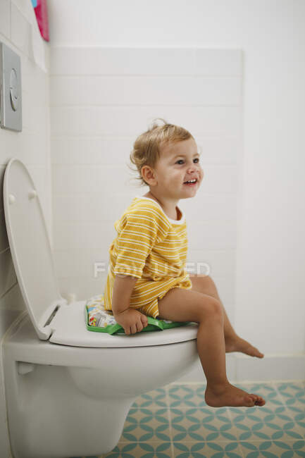 Портрет щасливої дівчини, що сидить на туалеті вдома — стокове фото