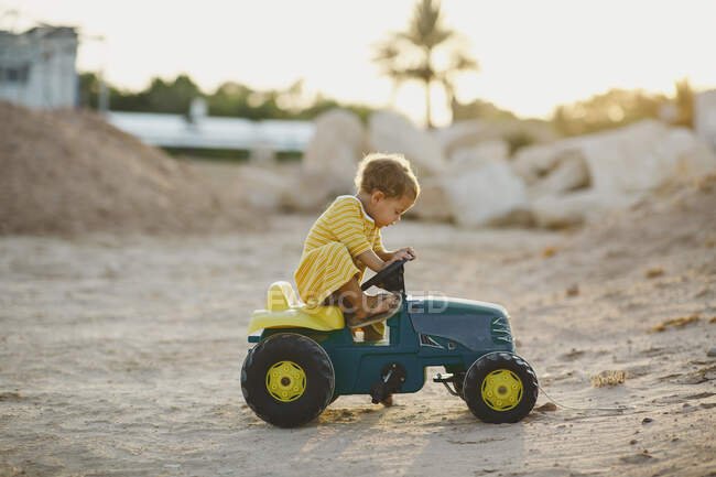 Enfant jouant sur tracteur jouet dans le désert — Photo de stock