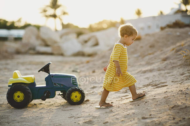 Тодлер грає на іграшковому тракторі в пустелі — стокове фото