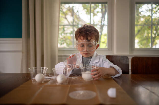 Мальчик проводит научный эксперимент, одетый в халат — стоковое фото