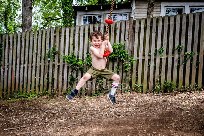 Menino no balanço da corda fazendo uma cara boba — Fotografia de Stock