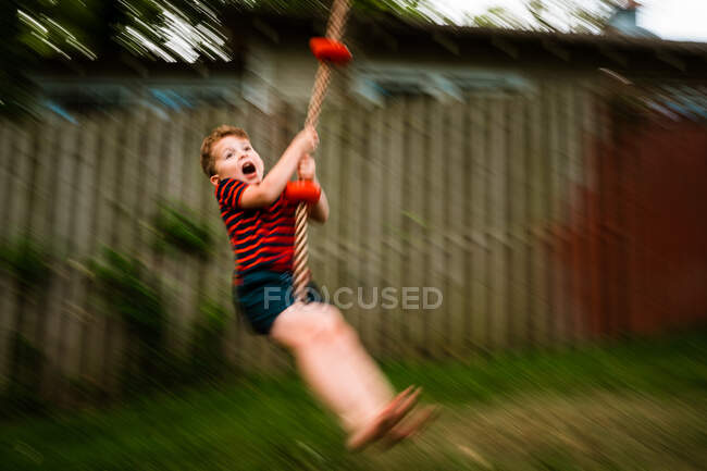 Young boy on rope swing in motion. — Stock Photo