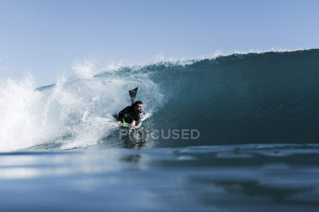 Bodyboarder surfeando una ola azul en el mar - foto de stock