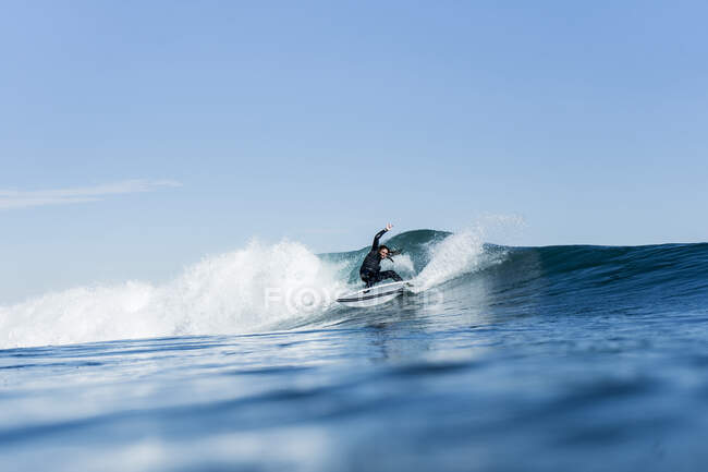 Hombre surfeando y haciendo una maniobra de surf en una ola en el mar - foto de stock