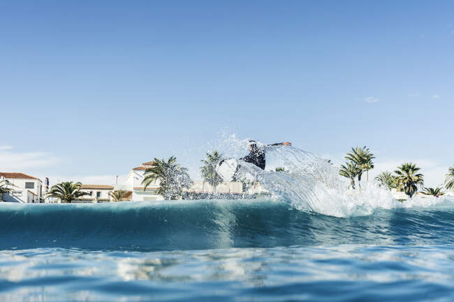 Hombre surfeando y haciendo una maniobra de surf en una ola en el mar - foto de stock