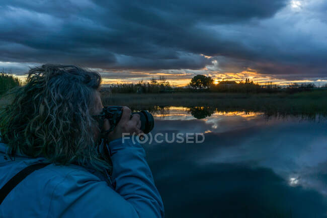 Женщина фотографирует пейзаж в сумерках в озере — стоковое фото