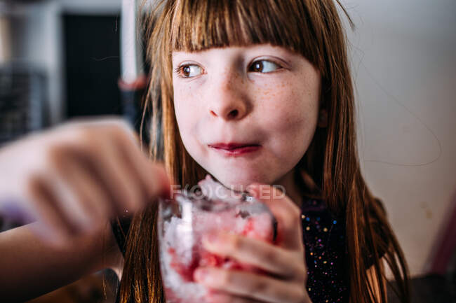 Портрет молодой девушки, поедающей снежный конус внутри — стоковое фото