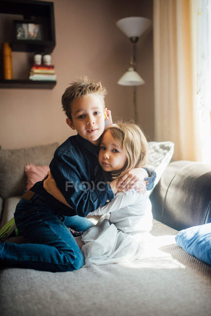 Hermano y hermana abrazándose en casa. - foto de stock