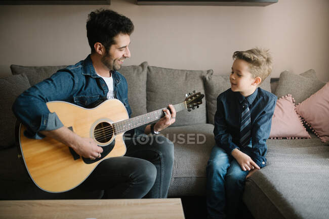 Um pai tocando guitarra para seu filho. — Fotografia de Stock