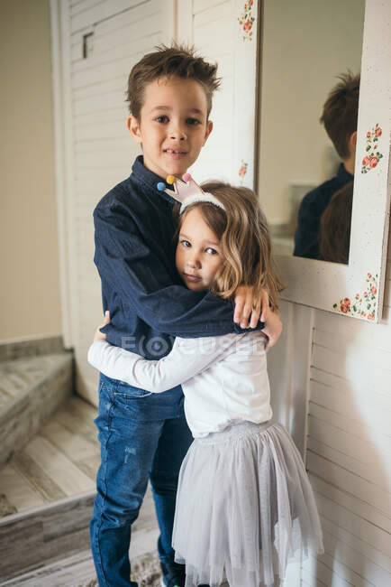 Hermano y hermana abrazando y mirando a la cámara. - foto de stock