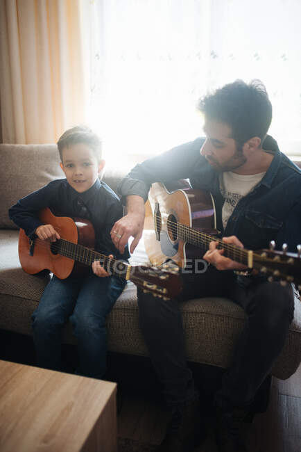 Папа с сыном играет на акустической гитаре. — стоковое фото