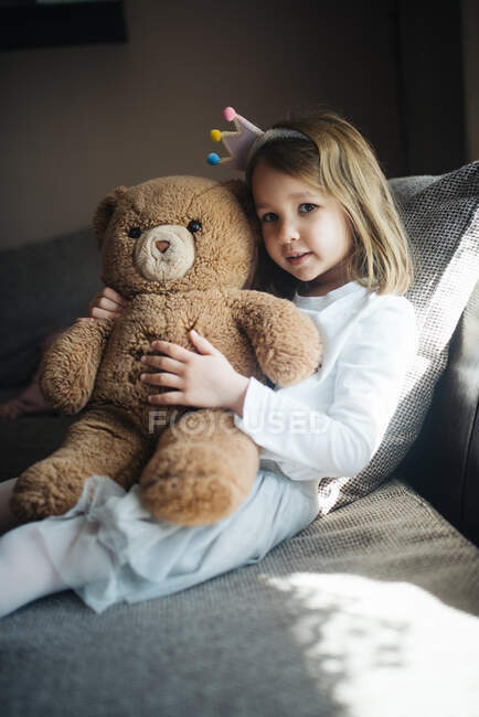 Menina feliz abraçando um ursinho de pelúcia em casa. — Fotografia de Stock