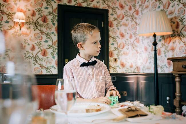 Menino vestido com uma camisa e gravata arco jogando em um casamento — Fotografia de Stock