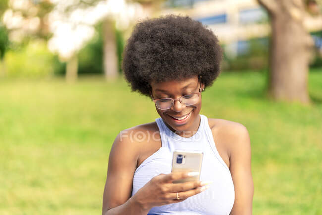 Афро волосся жінка використовує свій смартфон — стокове фото